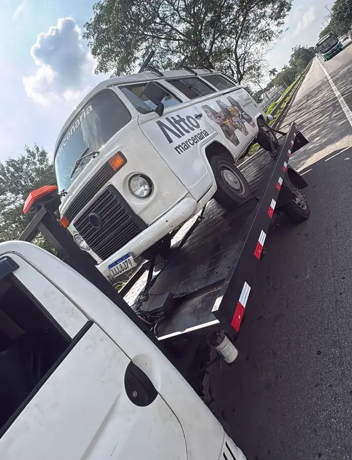 Kombi utilitária de marcenaria sendo rebocada em via com canteiro