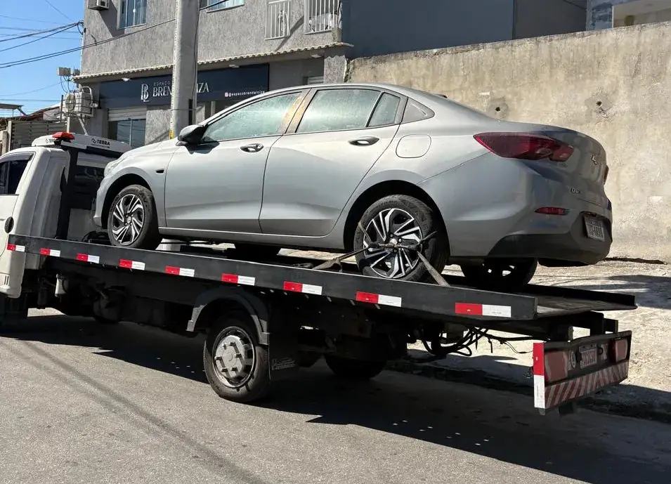 Chevrolet Onix prata na plataforma de reboque em rua comercial